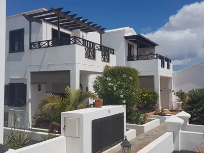 Whitewashed exterior of the residential complex at Playa Honda with balconies and garden